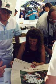 Sesquicentennial: Dad and Mike looking over Susys shoulder while she signs prints.